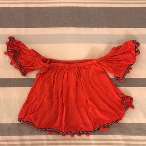 Off the shoulder shirt with pompoms.